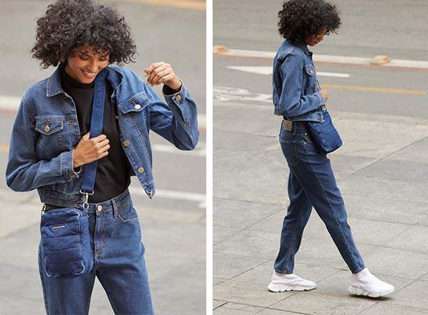 Jovem mulher elegante em uma jaqueta preta longa na moda em jeans